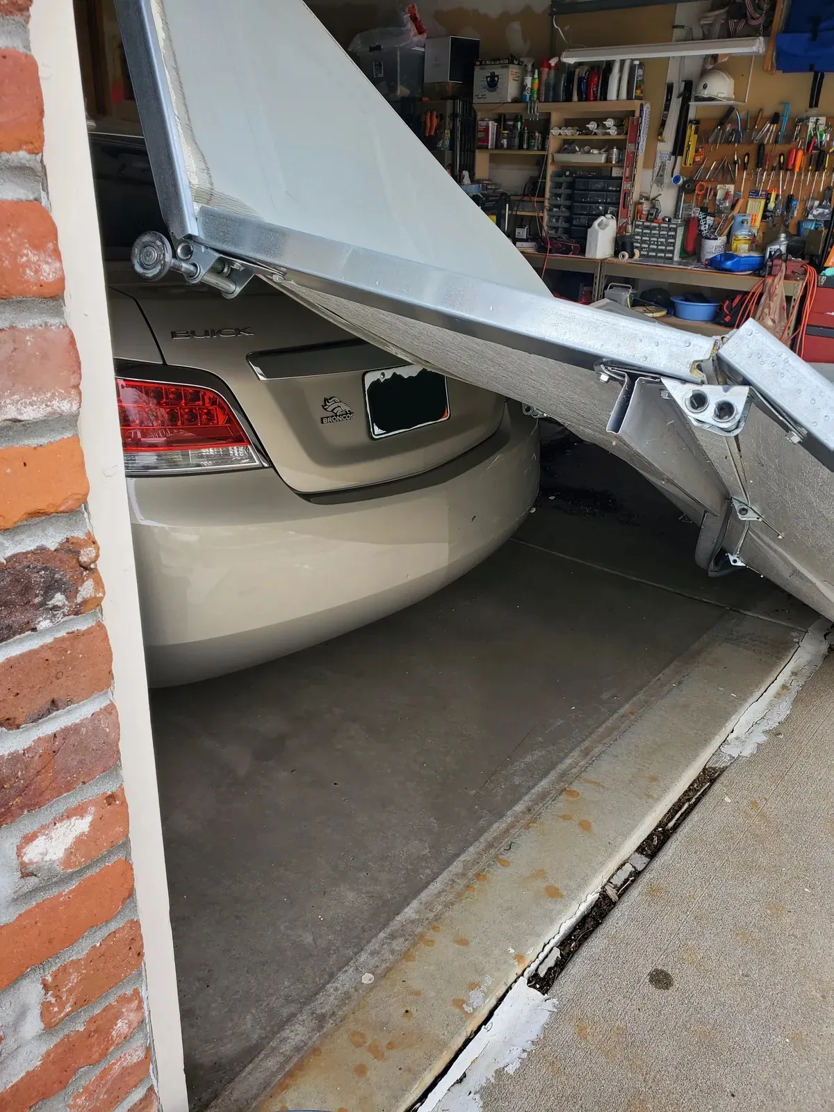 Off-track garage door repair in Arapahoe County, CO with identifying numbers blurred