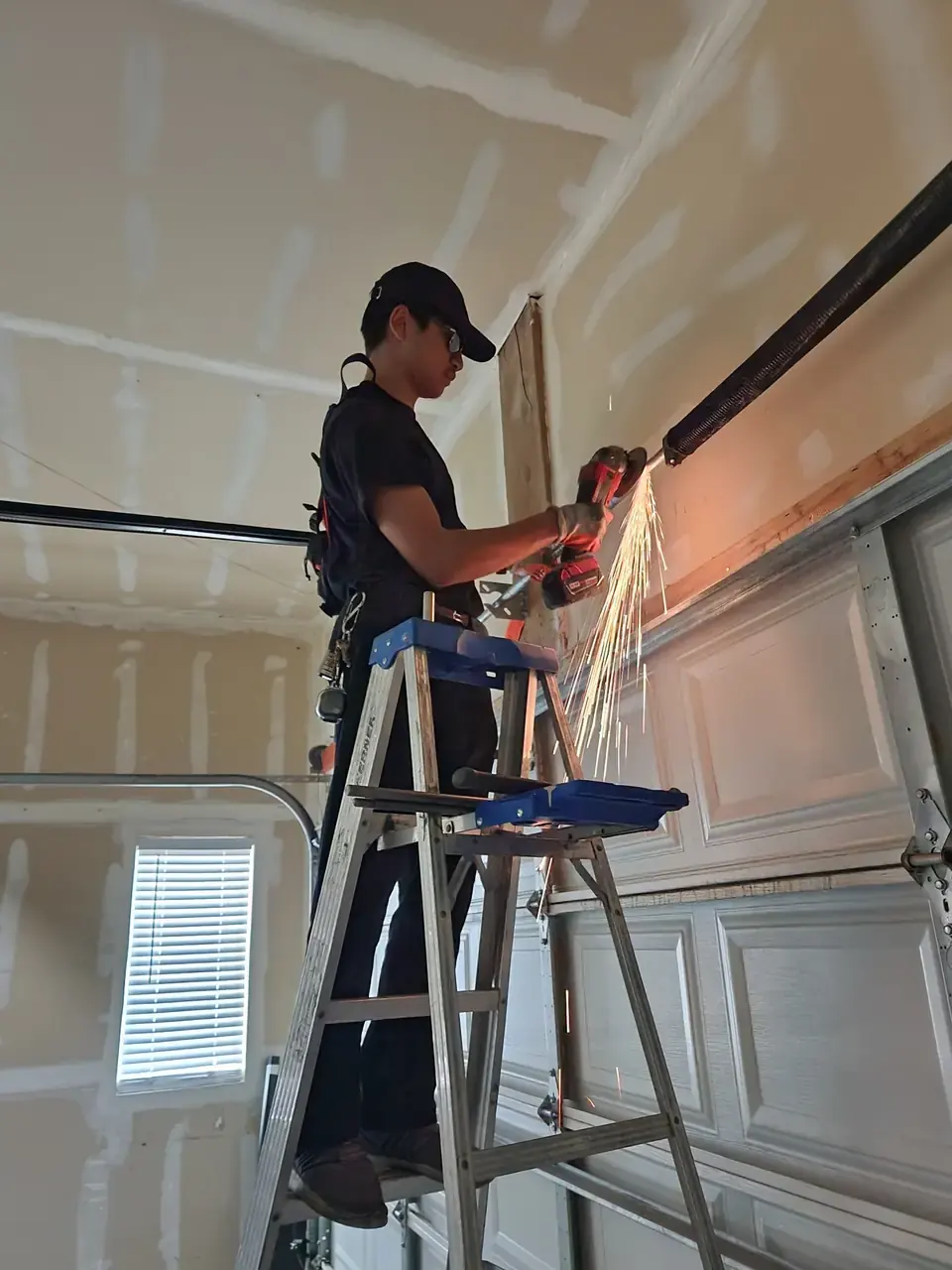 Technician working beside a garage door torsion spring